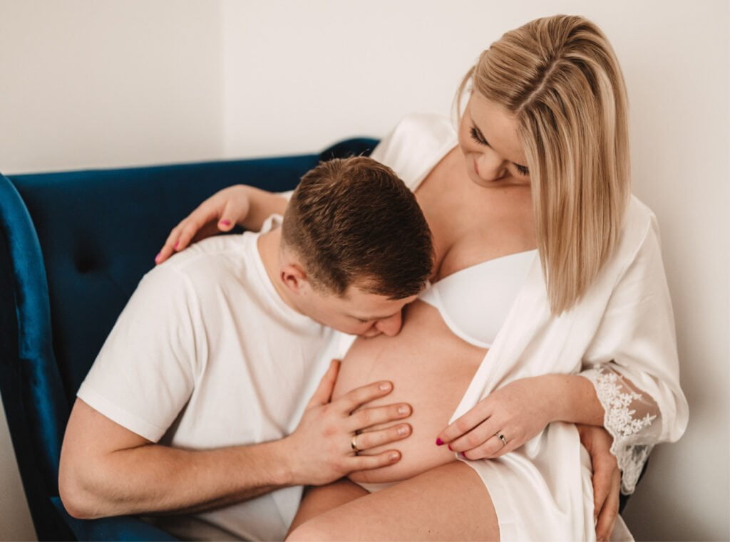 mąż całuje żonę w ciążowy brzuch
