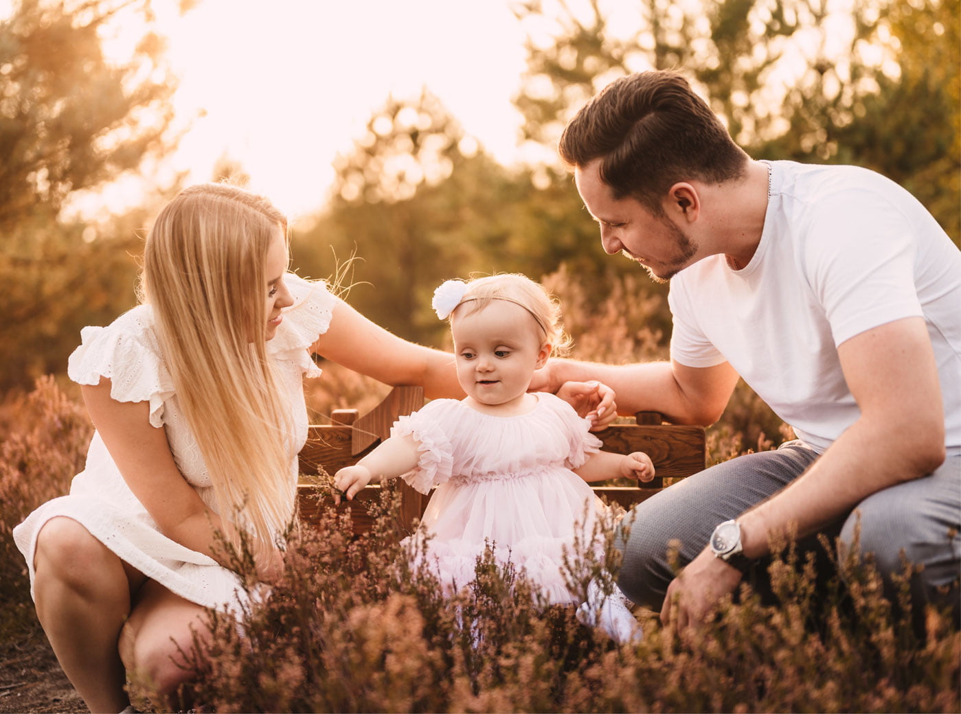mama, tata i dziecko siedzą w kwitnących wrzosach